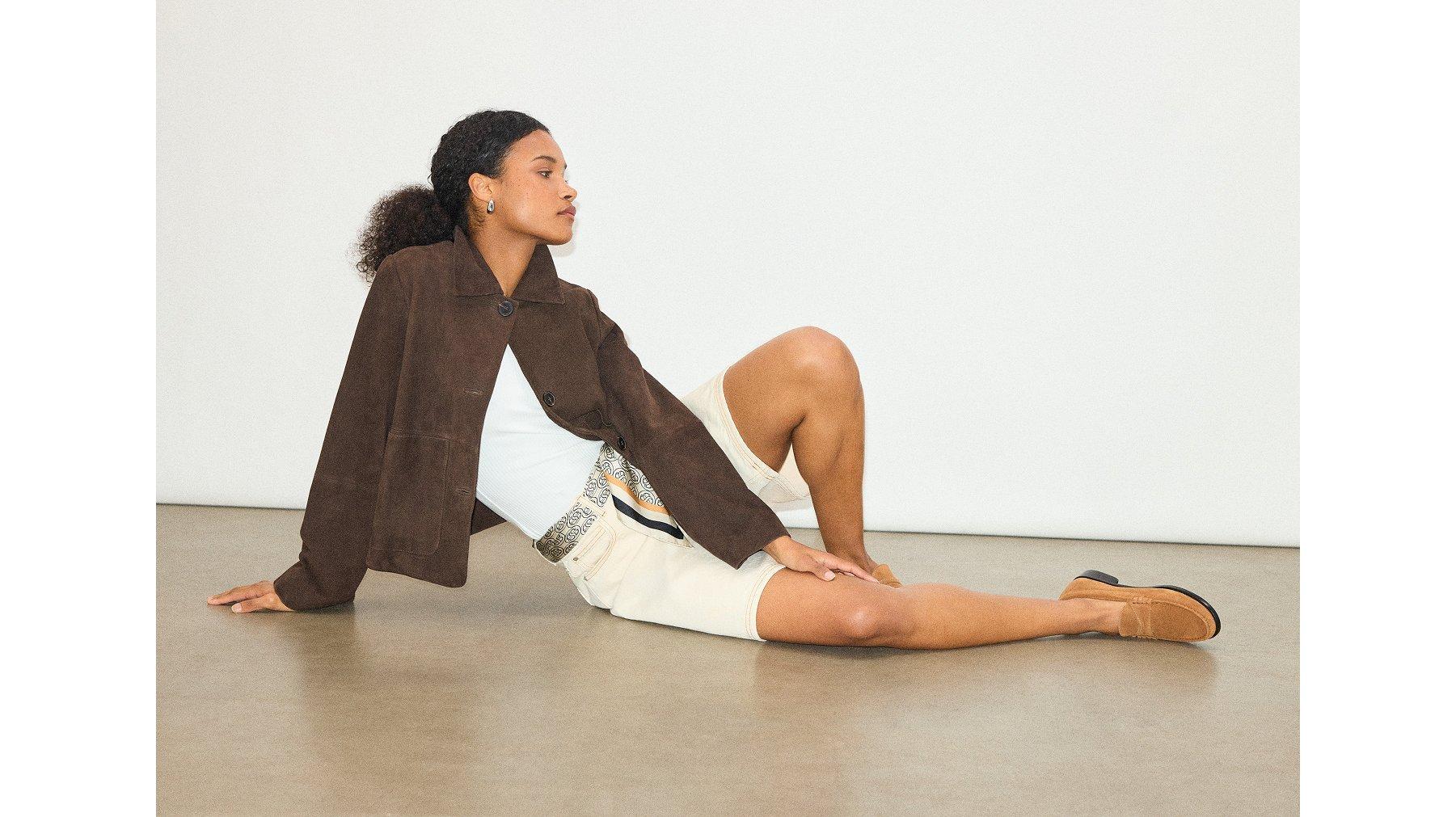 Model sitting on the floor in brown suede jacket